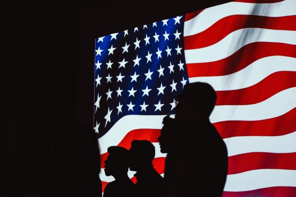 Silhouetten vor der Fahne der USA. Foto: Pexels, Brett Sayles